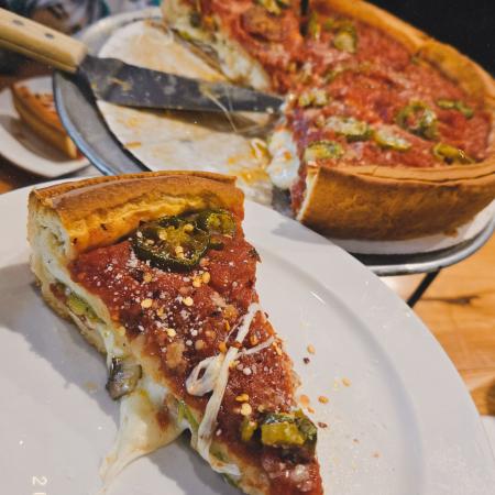 a pizza slice at the bottom left corner, with the rest of pizza in the back