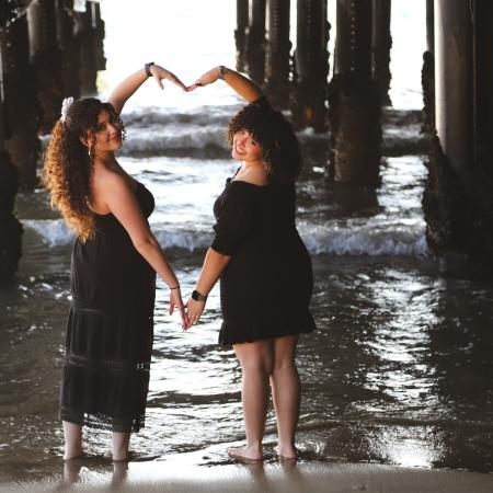 AJ and Alli making a heart with their arms at the beach